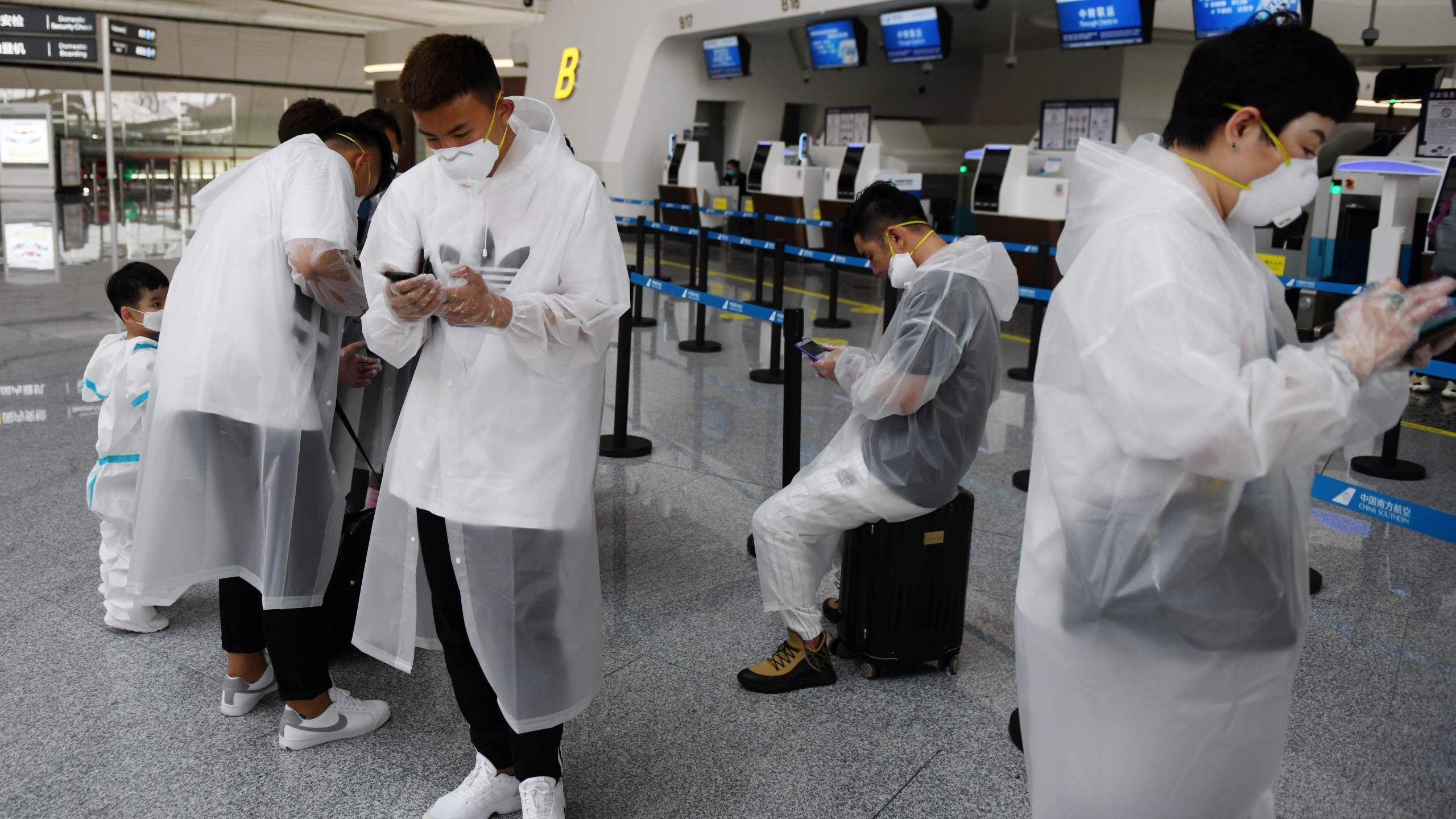 People wear protective clothing amid concerns of the COVID-19 coronavirus as they wait at a check-in counter at Beijing Daxing Airport on the eve of a five-day national holiday on April 30, 2020.(GREG BAKER/AFP via Getty Images)