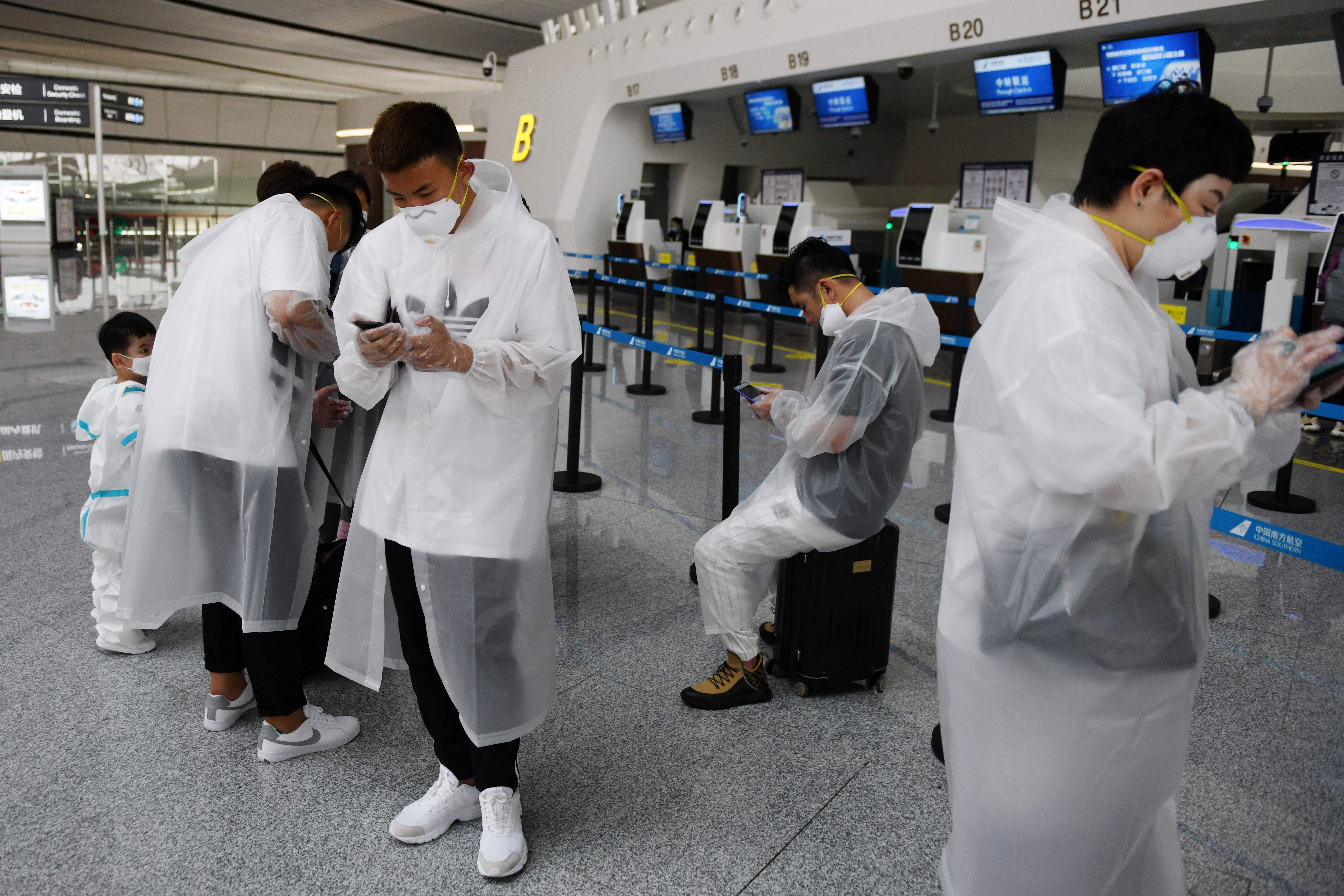 People wear protective clothing amid concerns of the COVID-19 coronavirus as they wait at a check-in counter at Beijing Daxing Airport on the eve of a five-day national holiday on April 30, 2020.(GREG BAKER/AFP via Getty Images)