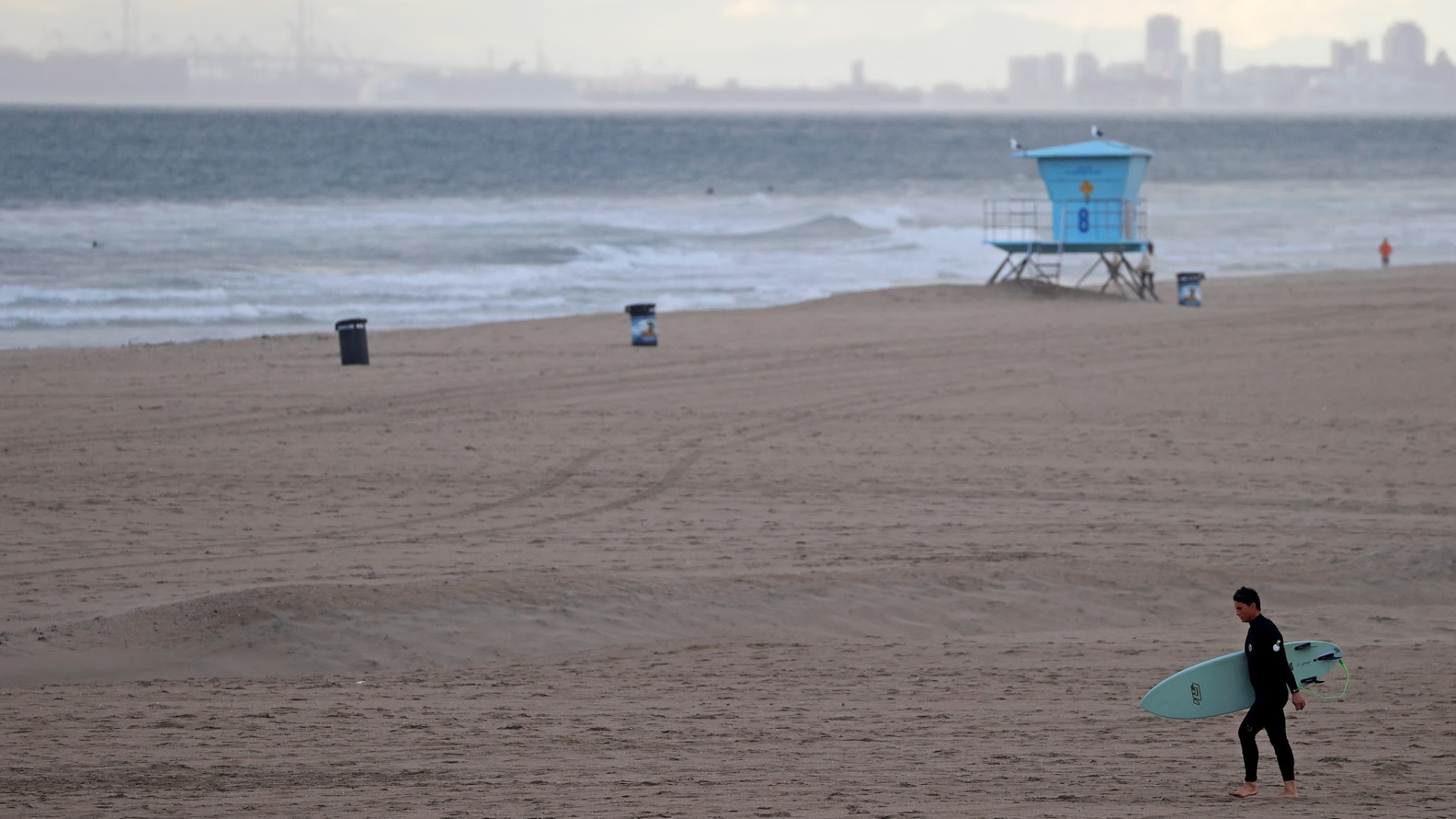 A surfer walks on the beach on March 19, 2020 in Huntington Beach, California. (Michael Heiman/Getty Images)