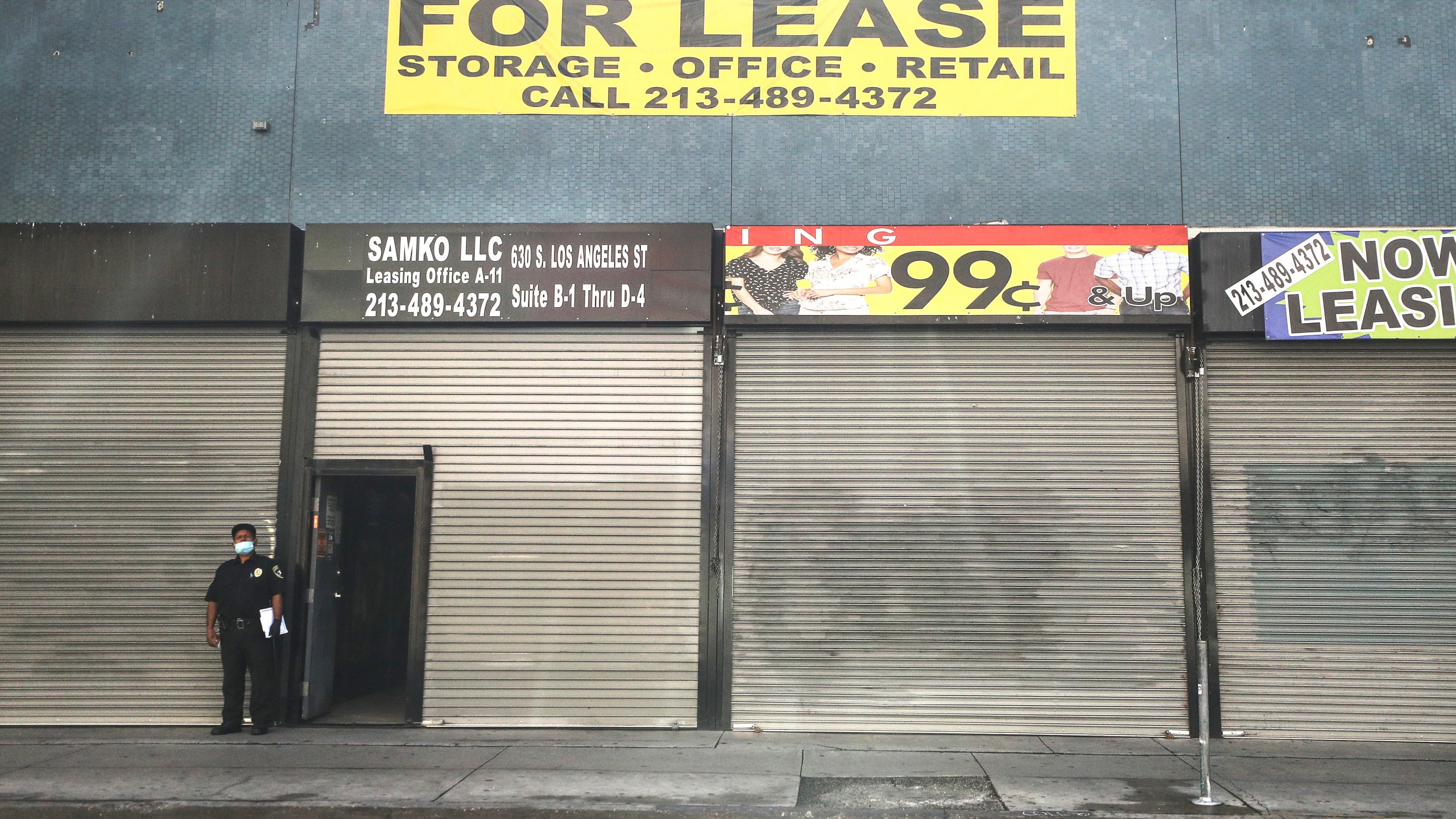 A security guard wears a face mask while standing outside shuttered shops and a 'For Lease' sign amid the global coronavirus pandemic on March 30, 2020 in Los Angeles, California. (Mario Tama/Getty Images)