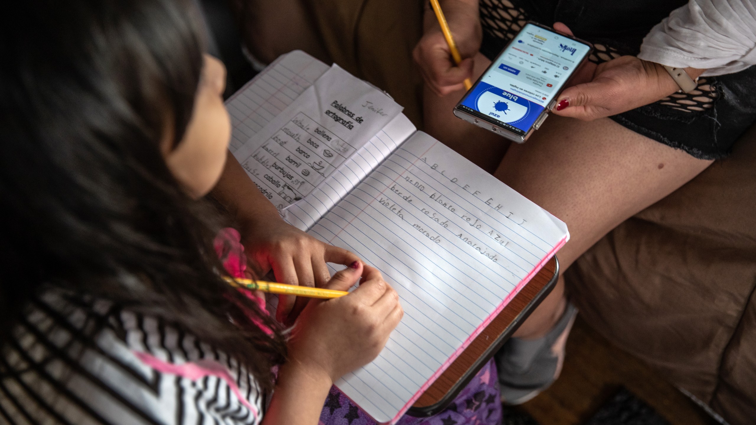 A mother and daughter, 8, from Honduras, recovering from fever, study English on March 30, 2020, in Mineola, New York. The third-grader has been out of school for several weeks — because the family has no internet and she has not been able to take part in distance learning with her classmates. (John Moore/Getty Images)