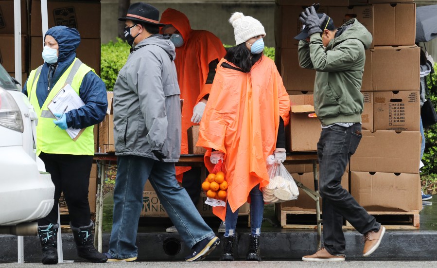 A volunteer holds food to be distributed to a family at a Los Angeles Regional Food Bank distribution for those in need as the coronavirus pandemic continues on April 9, 2020 in Van Nuys. (Mario Tama/Getty Images)