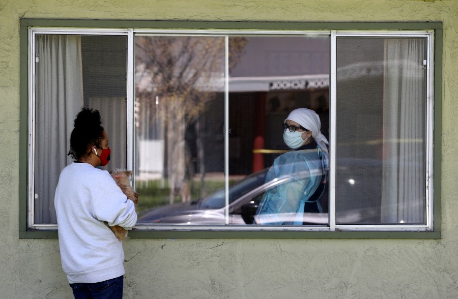 Adrina Rodriguez (L) talks with a nurse through a window as she visits her father who is a patient at the Gateway Care and Rehabilitation Center that has tested negative for COVID-19 on April 14, 2020, in Hayward, California. (Justin Sullivan/Getty Images)