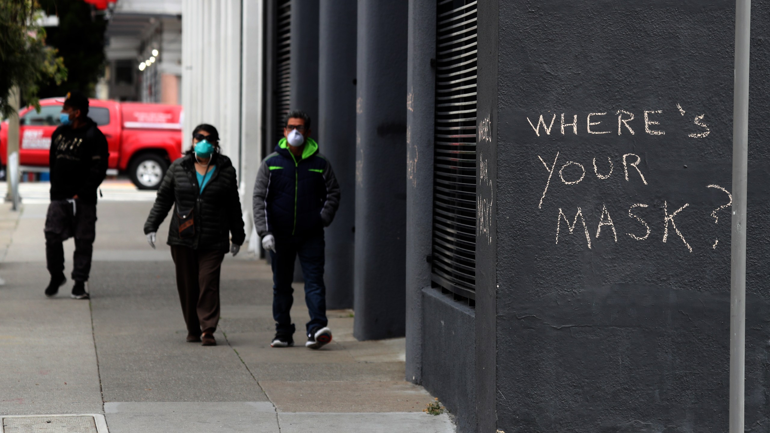 Pedestrians walk by graffiti encouraging the wearing of masks on April 20, 2020, in San Francisco, California. (Justin Sullivan/Getty Images)