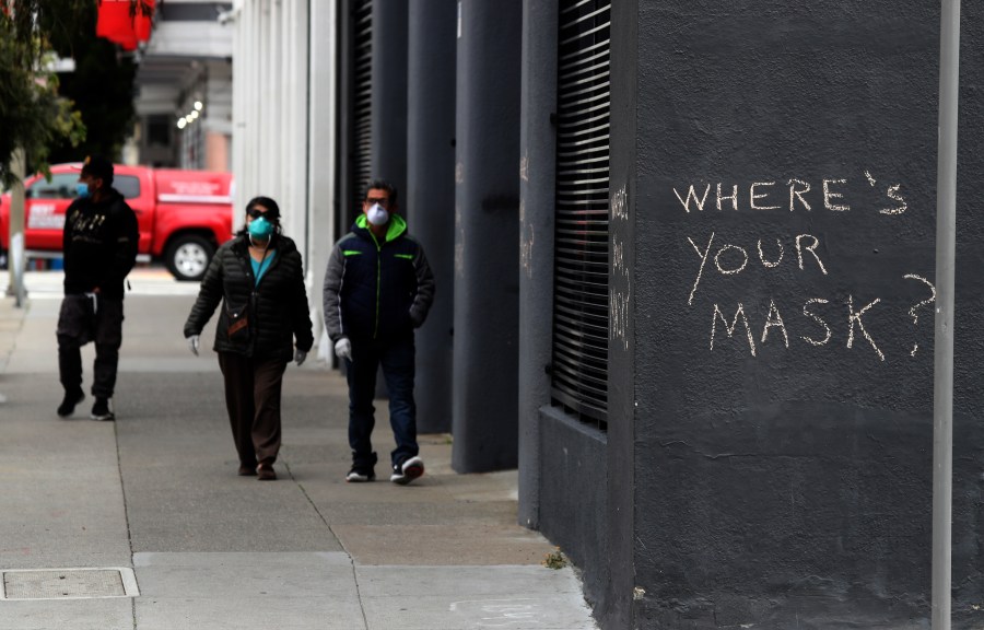 Pedestrians walk by graffiti encouraging the wearing of masks on April 20, 2020, in San Francisco, California. (Justin Sullivan/Getty Images)