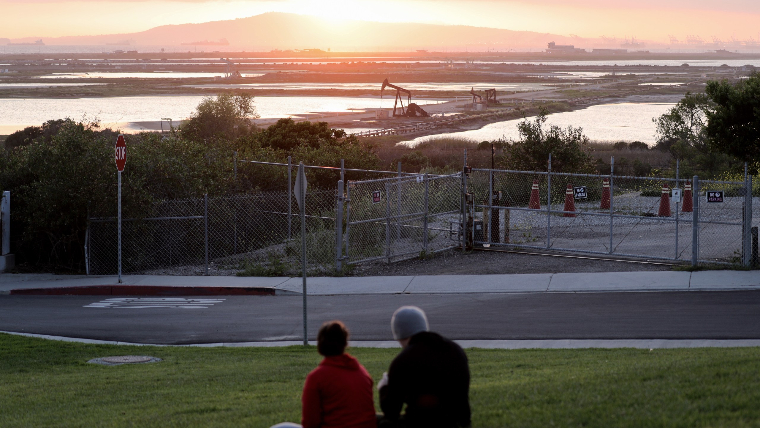 People sit on a hillside overlooking oil pumpjacks at the Huntington Beach Oil Fields amidst the coronavirus pandemic on April 20, 2020 in Huntington Beach, California. (Mario Tama/Getty Images)