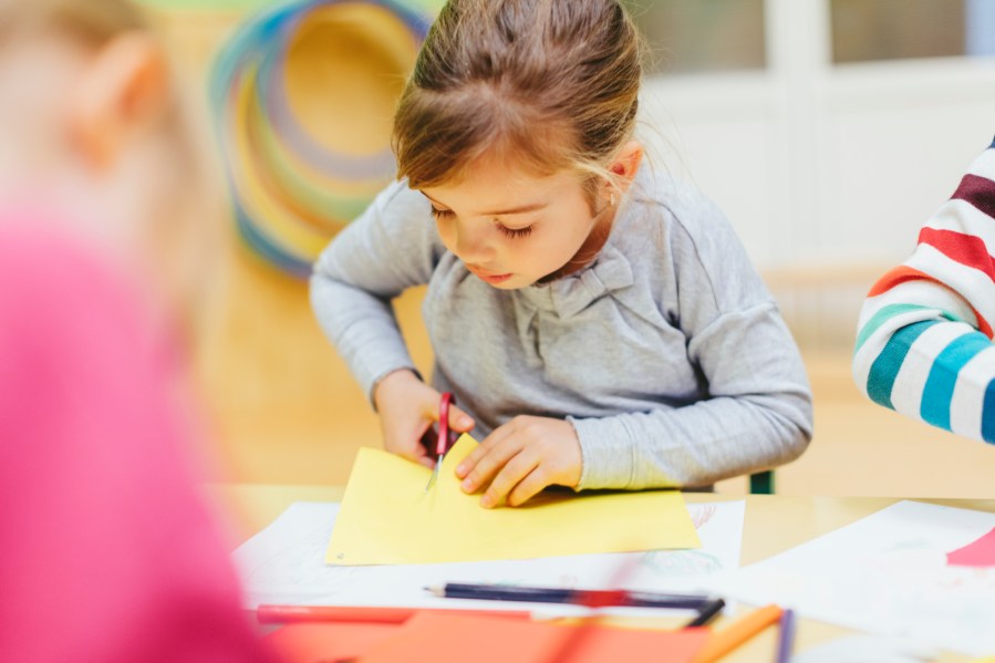 A preschooler cuts colored paper with scissors in this file photo. (Getty Images)