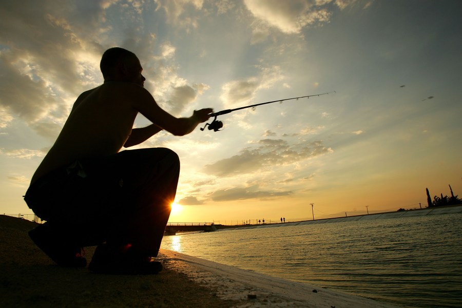 Tyrone Burchett casts his fishing line into the California Aqueduct, which carries water hundreds of miles from northern California to the state's southern cities, near his home at sunset on July 27, 2005, in Palmdale, California. (David McNew/Getty Images)