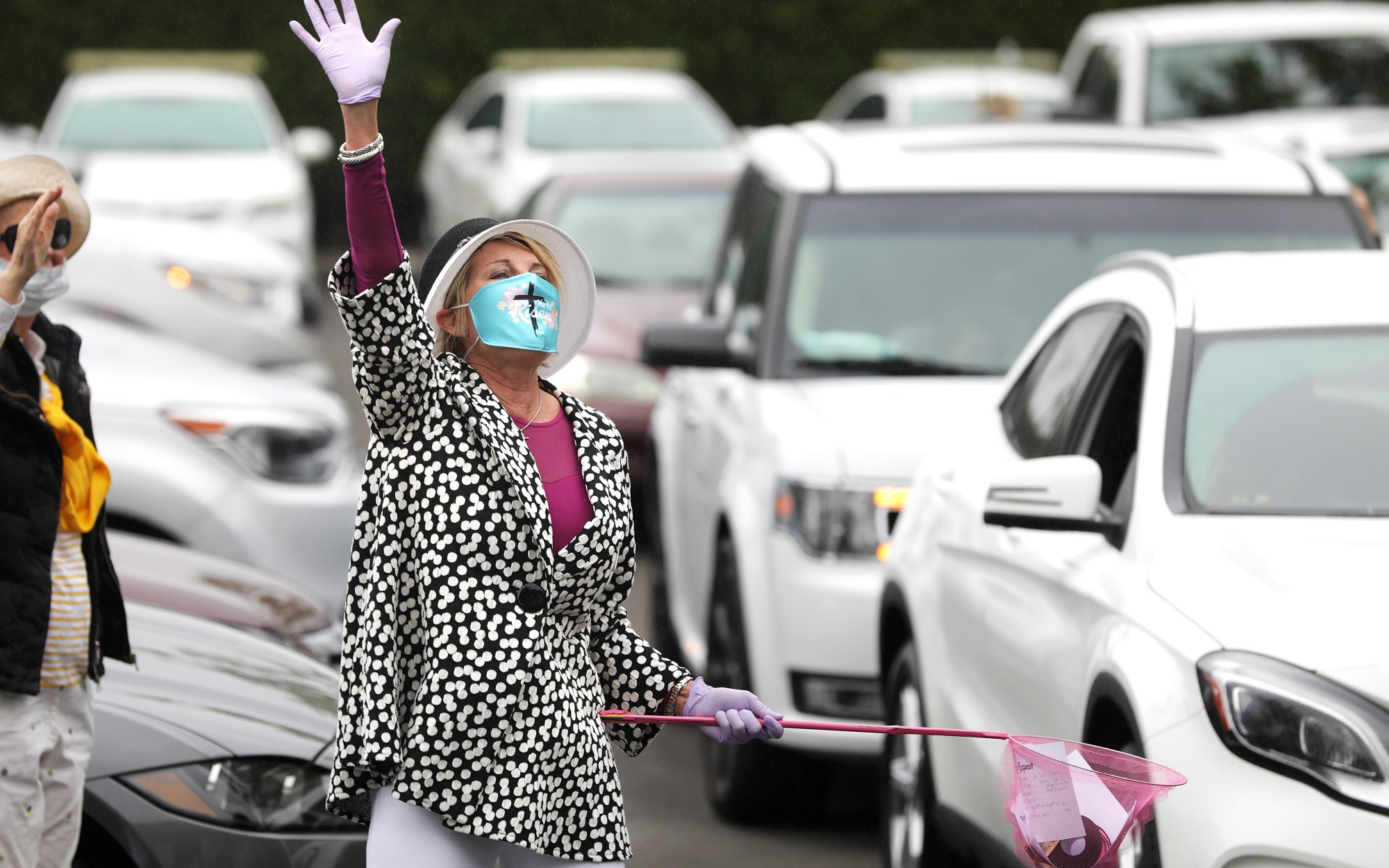 MaryAnn Lawson collects prayer requests from people gathered in their cars in a Santa Ana parking lot for an Easter service by the Rev. Robert A. Schuller.(Christina House / Los Angeles Times)