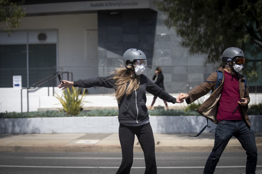 A couple wear masks, helmets and eye protection while skateboarding in Beverly Hills in March 2020. (Credit: Francine Orr / Los Angeles Times)