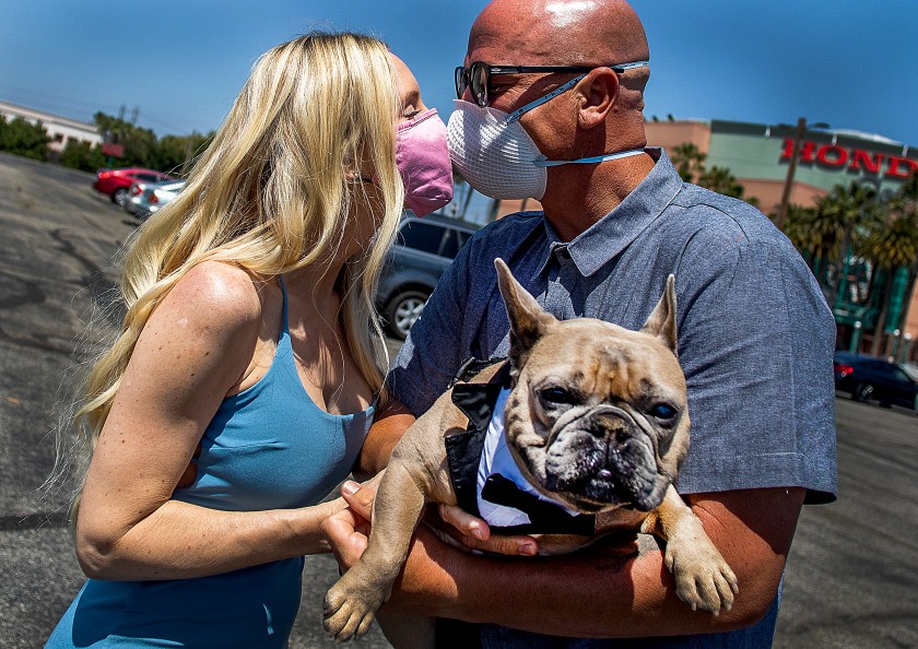 Tracey and Chad Robbins, with their dog, Huggy, kiss after their wedding ceremony at the Honda Center parking lot in Anaheim in April 2020. (Apu Gomes / AFP/Getty Images)