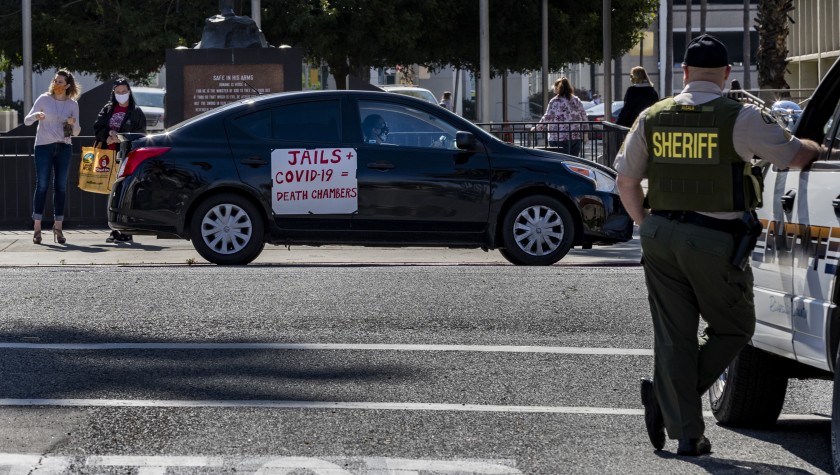 A Riverside County sheriff’s deputy keeps watch during a car rally to protest conditions in Riverside County jails, where there has been a coronavirus outbreak. (Gina Ferazzi / Los Angeles Times)