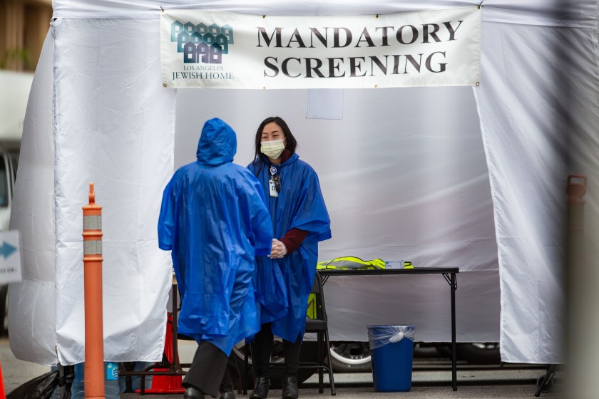 A worker at Eisenberg Village, an assisted living facility in Reseda conducts screenings for people with coronavirus symptoms in March 2020. (Jason Armond / Los Angeles Times)