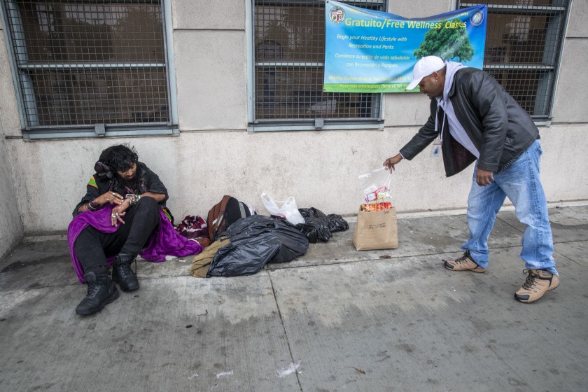 Outreach nurse Kenya Smith, right, leaves food for Davis Soto, who is homeless, in March 2020 in Los Angeles. (Brian van der Brug / Los Angeles Times)