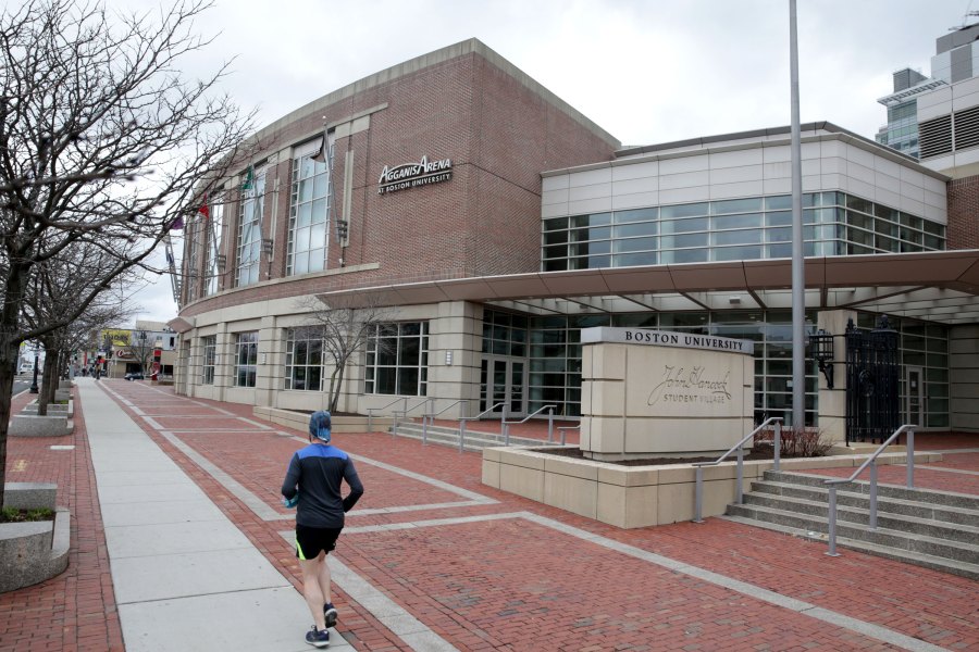 A person runs past Agganis Arena at Boston University along Commonwealth Ave. in Boston on March 25, 2020. Agganis Arena was set to host the Women's Frozen Four hockey tournament, but the event was cancelled. The coronavirus pandemic has postponed, suspended or cancelled many major sporting events and seasons. (Jonathan Wiggs/The Boston Globe via Getty Images)