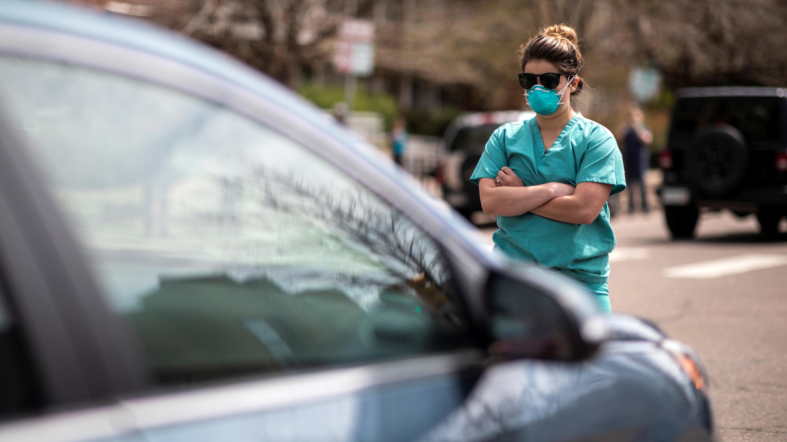 A health care worker stands in the street in counterprotest to the hundreds of people demanding the stay-at-home order be lifted in Denver, Colorado on April 19, 2020. (Alyson McClaran/Reuters)