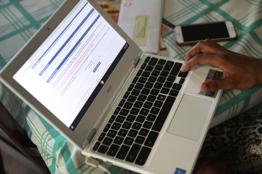 A Florida woman uses her computer to fill out the application for unemployment benefits after being laid off from her job at the Fort Lauderdale–Hollywood International Airport on March 27, 2020, in Florida. (Joe Raedle/Getty Images via CNN)