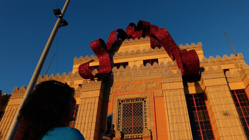 A visitor snaps a photo beneath the Citadel Outlets’ holiday bow in an undated photo. (Gary Coronado / Los Angeles Times)