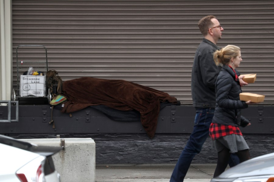 A homeless person sleeps on a loading dock in San Francisco on Dec. 5, 2019. (Credit: Justin Sullivan / Getty Images)