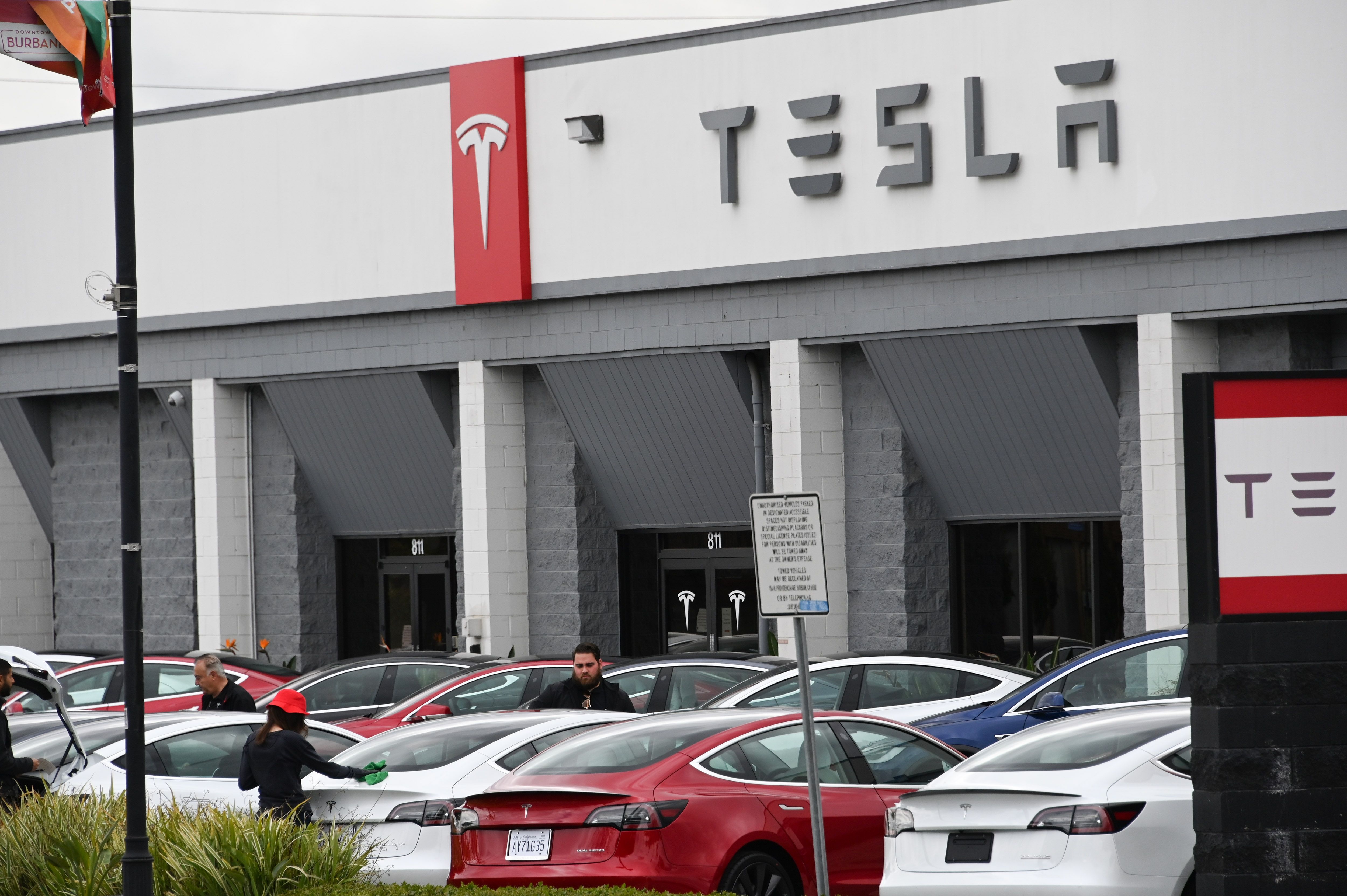 Tesla employees work outside a Tesla showroom in Burbank on March 24, 2020. (Credit: Robyn Beck / AFP / Getty Images)