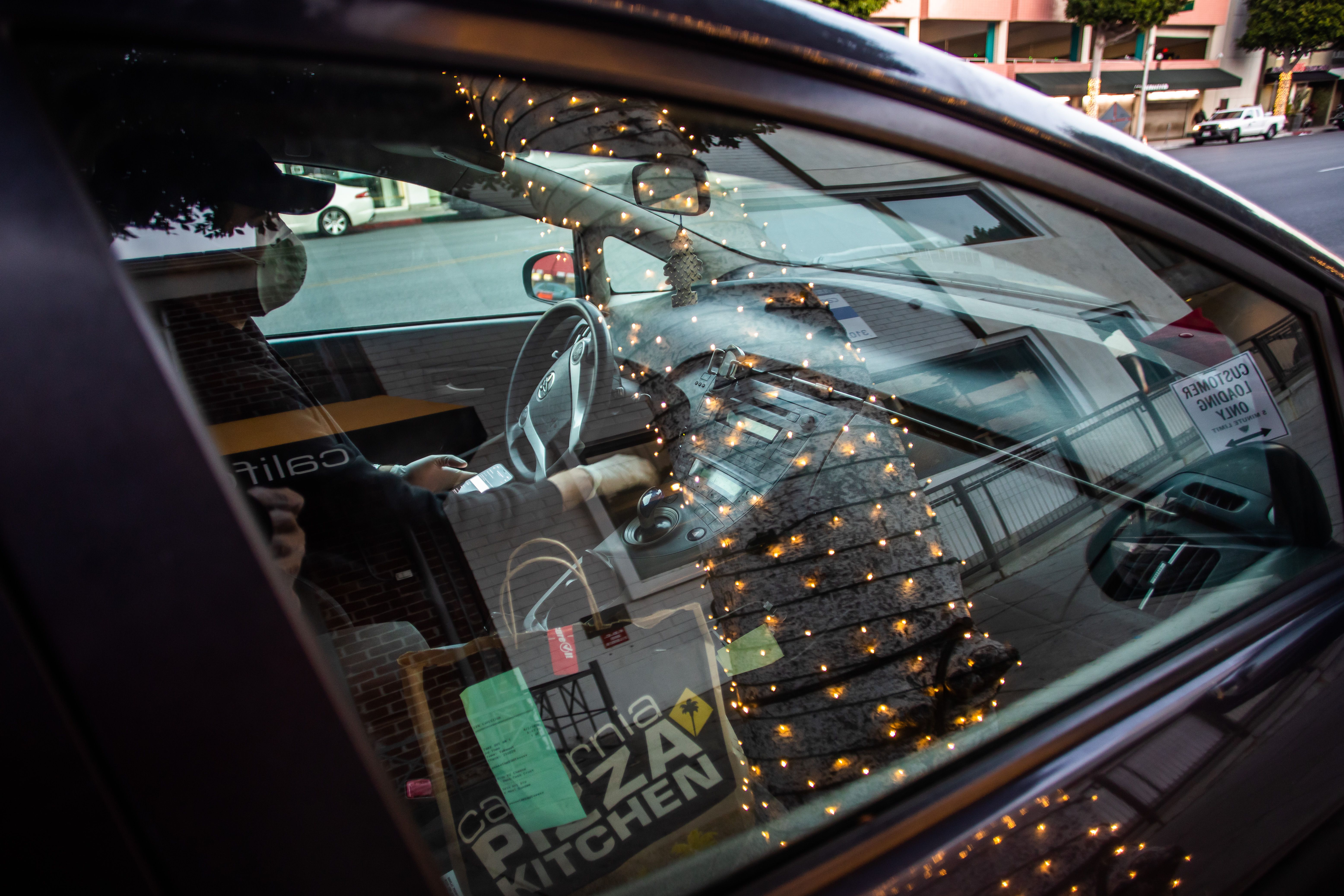 Musician Lucas Goes wears a mask as he drives to deliver food for a delivery app in Beverly Hills on April 2, 2020, after losing his job during the coronavirus outbreak. (Apu Gomes / AFP / Getty Images)