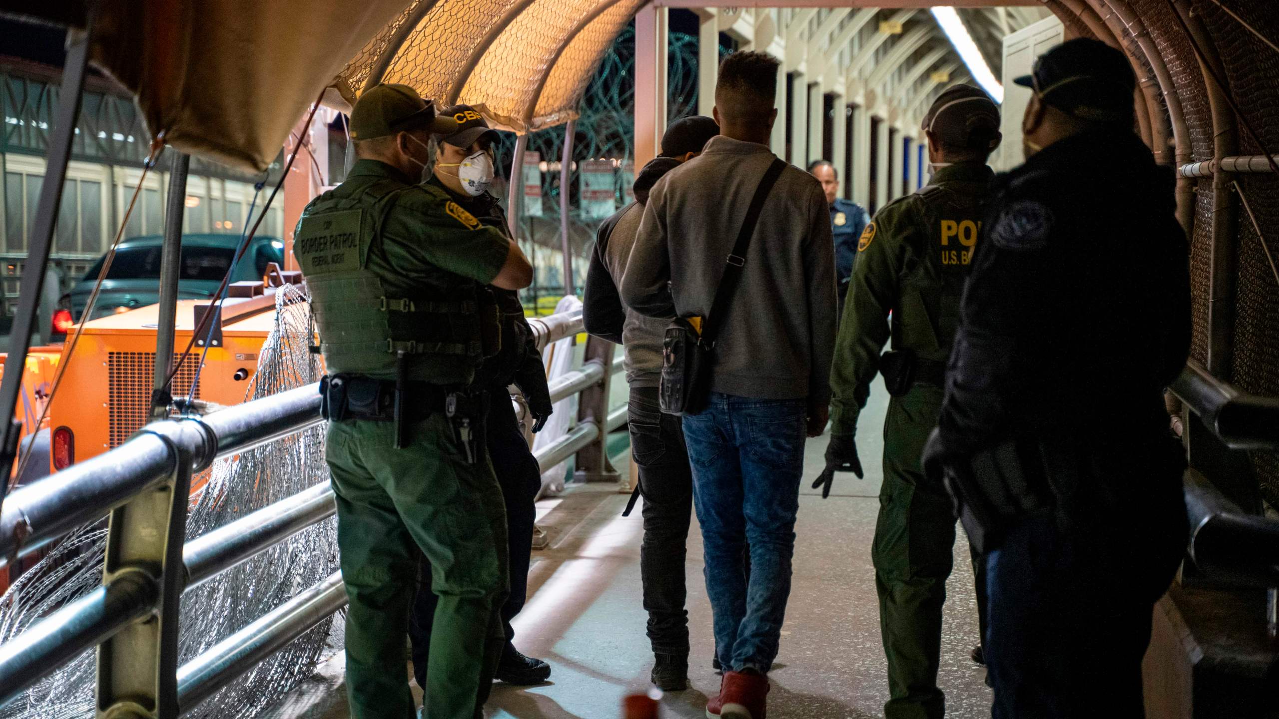 U.S. Border Patrol and Customs and Border Protection agents escort asylum applicants down to the U.S. side of the the Paso del Norte International Bridge in El Paso, Texas, on April 1, 2020. (Paul Ratje / AFP / Getty Images)