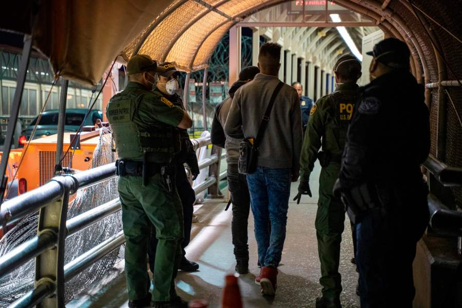 U.S. Border Patrol and Customs and Border Protection agents escort asylum applicants down to the U.S. side of the the Paso del Norte International Bridge in El Paso, Texas, on April 1, 2020. (Paul Ratje / AFP / Getty Images)