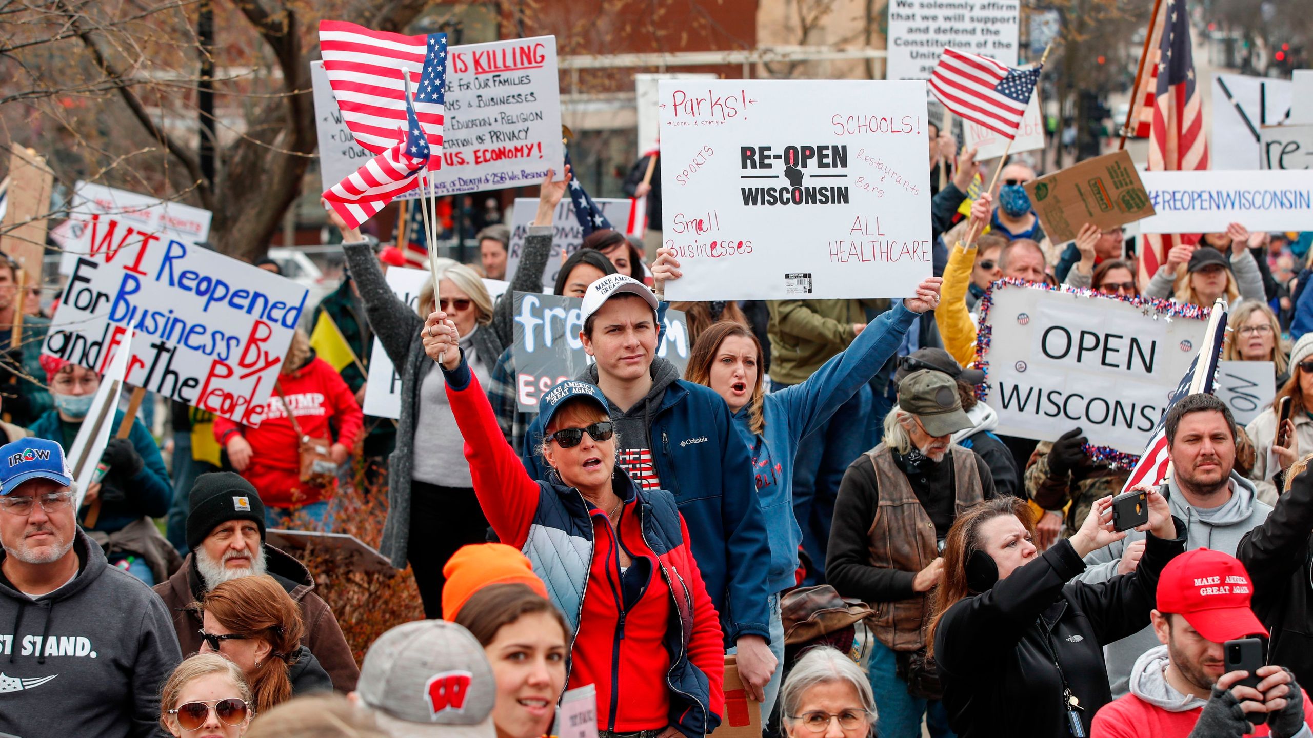 People hold signs during a protest against the coronavirus shutdown in front of the State Capitol in Madison, Wisconsin, on April 24, 2020. (KAMIL KRZACZYNSKI/AFP via Getty Images)