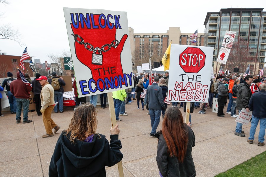 People hold signs during a protest against the coronavirus shutdown in front of the State Capitol in Madison, Wisconsin, on April 24, 2020. (KAMIL KRZACZYNSKI/AFP via Getty Images)