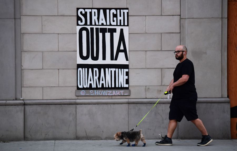 A man walks his dogs past a public art installation in Los Angeles on April 28, 2020. (FREDERIC J. BROWN/AFP via Getty Images)