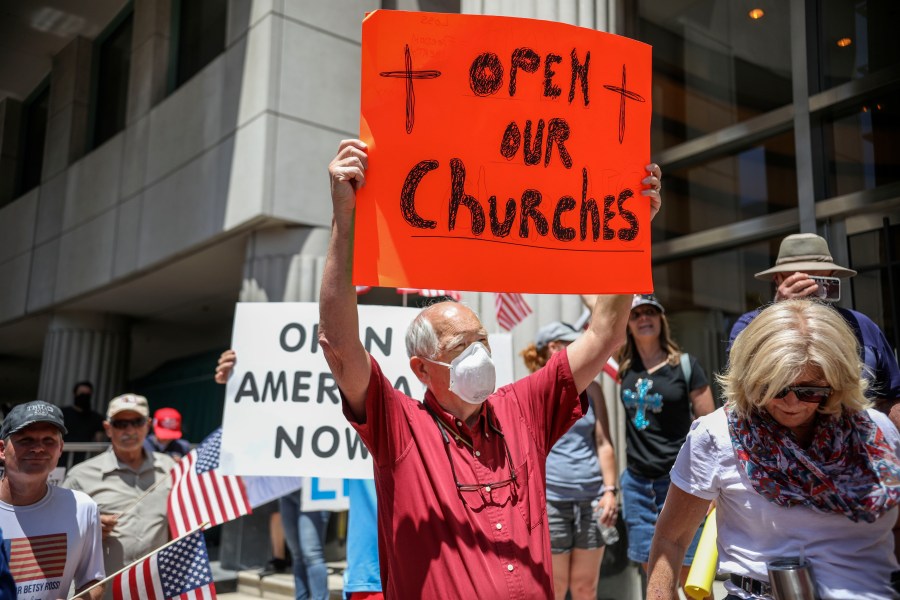 Demonstrators, holding signs demanding their church reopen, protest during a rally to reopen California and go against Stay-At-Home directives on May 1, 2020 in San Diego. Rallies have been held at several state capitols across the country as protesters express their deep frustration with the stay-at-home orders that are meant to stem the spread of the novel coronavirus. (Sandy Huffaker / AFP via Getty Images)