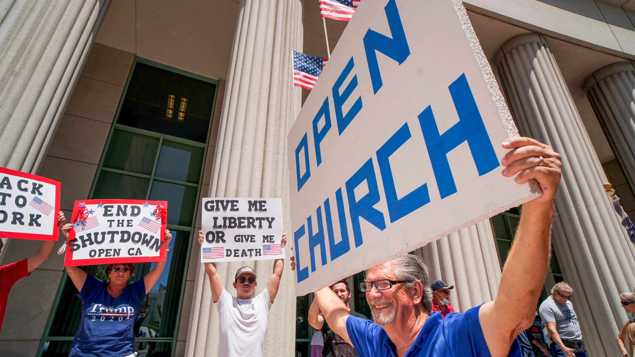 Demonstrators hold signs demanding their church to reopen during a rally against stay-home orders in San Diego on May 1, 2020. (Sandy Huffaker / AFP / Getty Images)