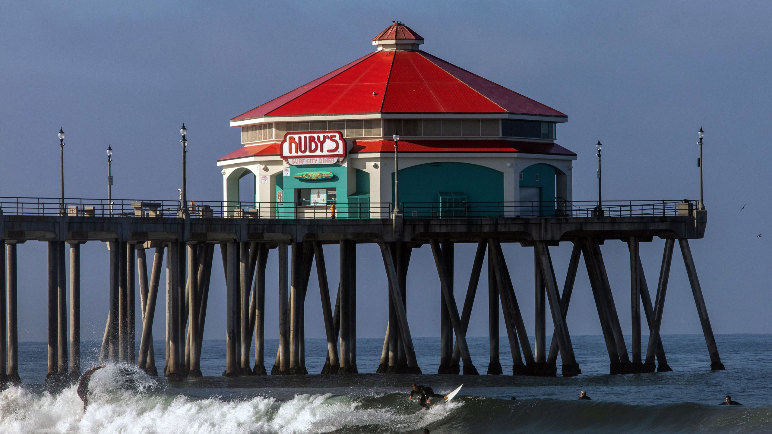 Surfers catch waves near the pier in Huntington Beach on May 2, 2020. (APU GOMES/AFP via Getty Images)