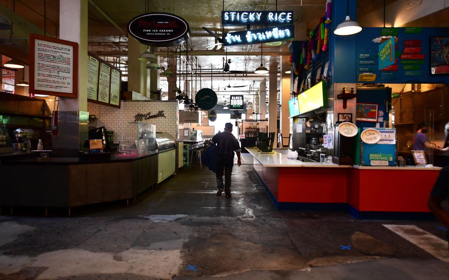 Some restaurants close as other remain open for takeout, observing new social distancing rules, with blue tape marked on the floor, at what would normally be a crowded lunctime scene at the Grand Central Market in Los Angeles, California on May 4, 2020. (FREDERIC J. BROWN/AFP via Getty Images)