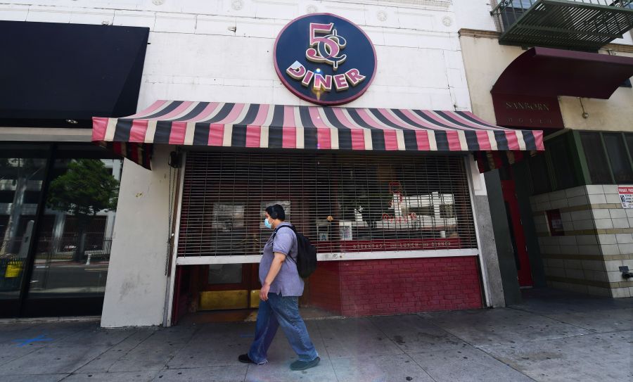 A pedestrian wears his face mask while walking past a closed Nickel Diner in Los Angeles on May 7, 2020. (FREDERIC J. BROWN/AFP via Getty Images)