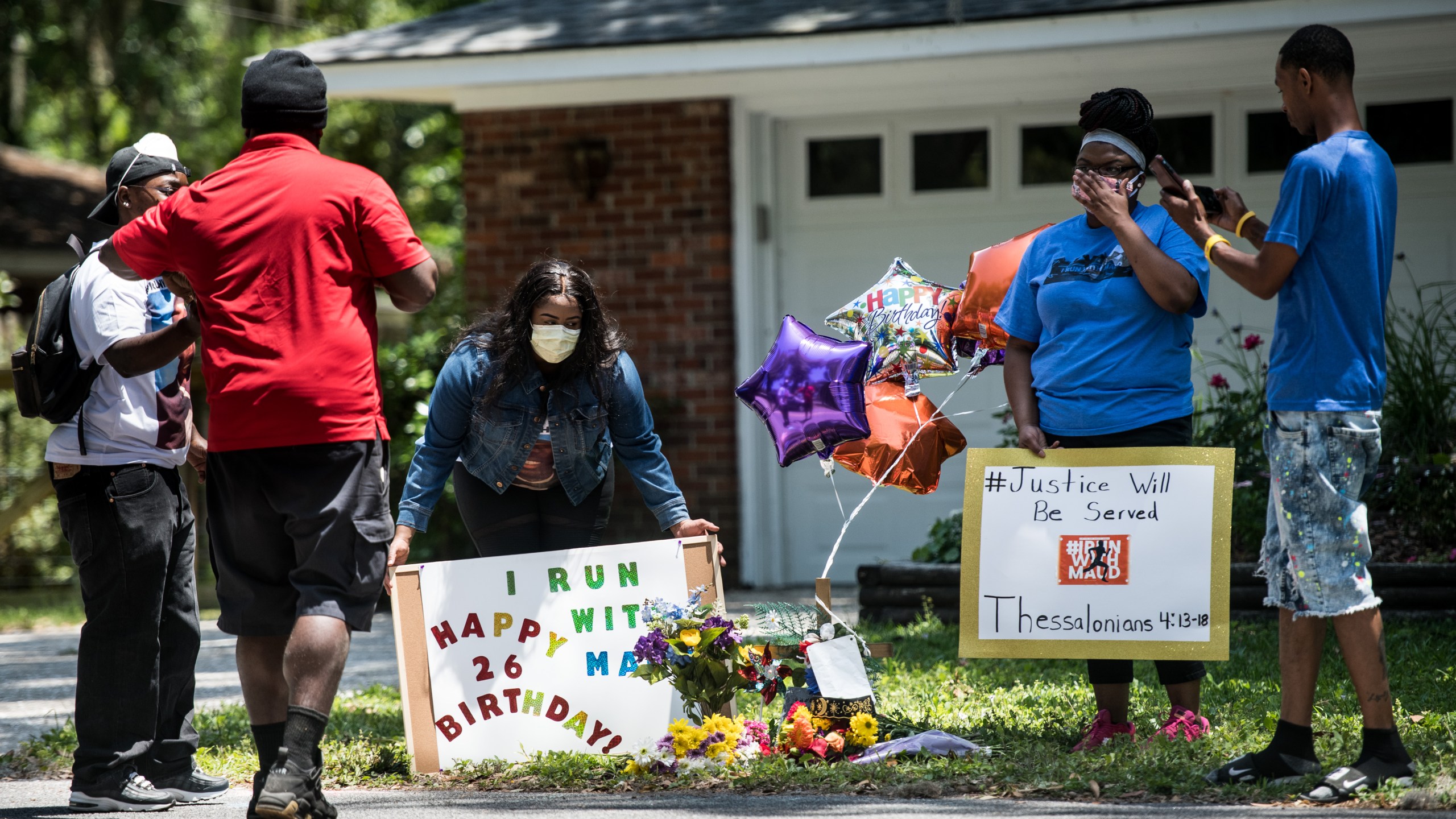 Demonstrators hold signs at a memorial for Ahmaud Arbery on May 8, 2020, near where he was shot and killed in Brunswick, Georgia. (Credit: Sean Rayford / Getty Images)