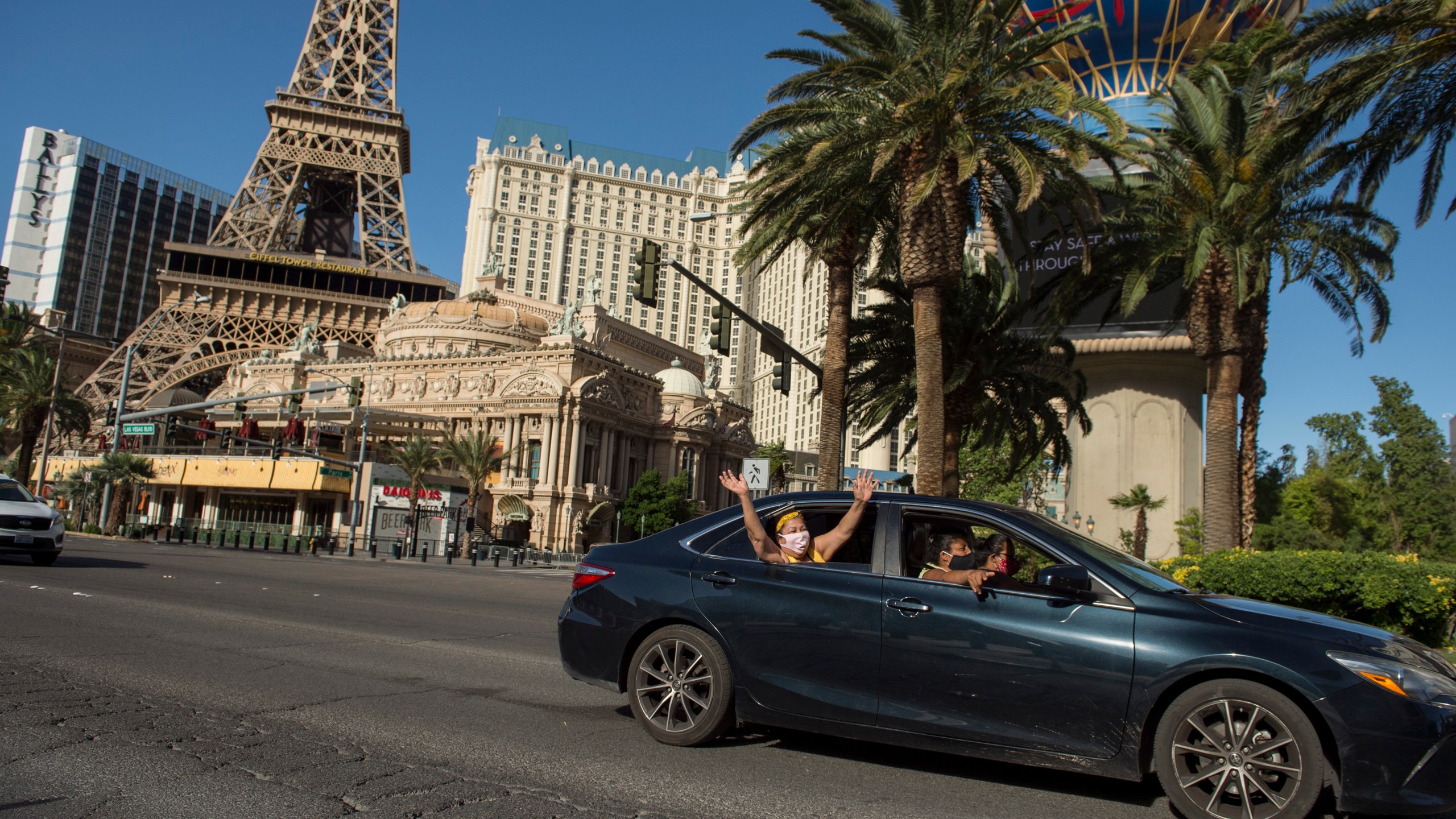 People reach outside their car, waving to onlookers, as members and supporters of Culinary Union 226 caravan down Las Vegas Strip calling attention to casinos to share re-opening plans and enforce strong protections for workers and visitors amid the coronavirus pandemic, in Nevada, on May 12, 2020. (BRIDGET BENNETT/AFP via Getty Images)