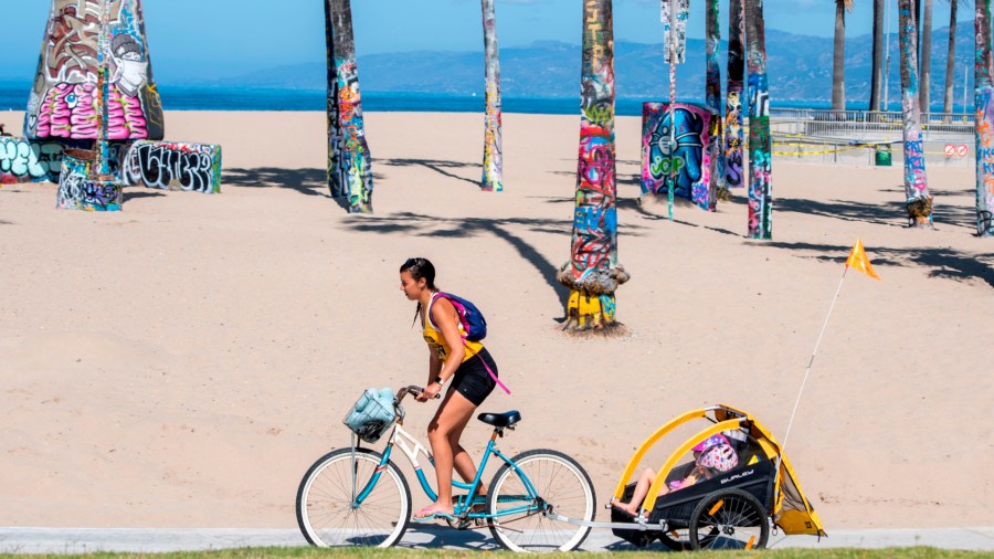 A person bikes on a closed path at Venice Beach on May 13, 2020. (VALERIE MACON/AFP via Getty Images)