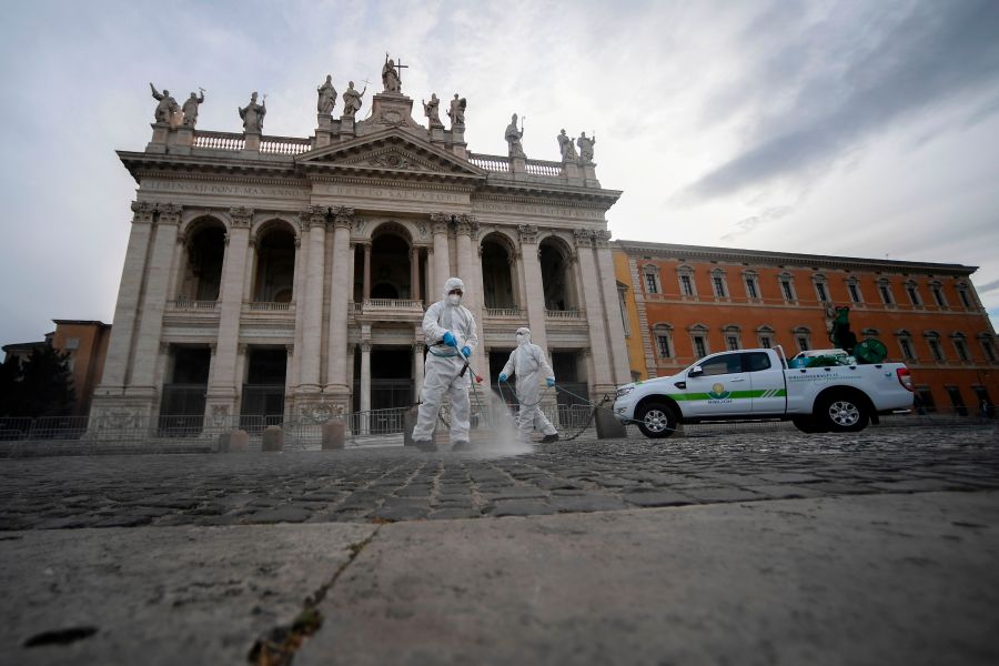 Employees of a disinfecting services company, wearing protective overalls and mask, spray sanitizer at the Archbasilica of Saint John Lateran (San Giovanni in Laterano) in Rome on May 15, 2020. (FILIPPO MONTEFORTE/AFP via Getty Images)