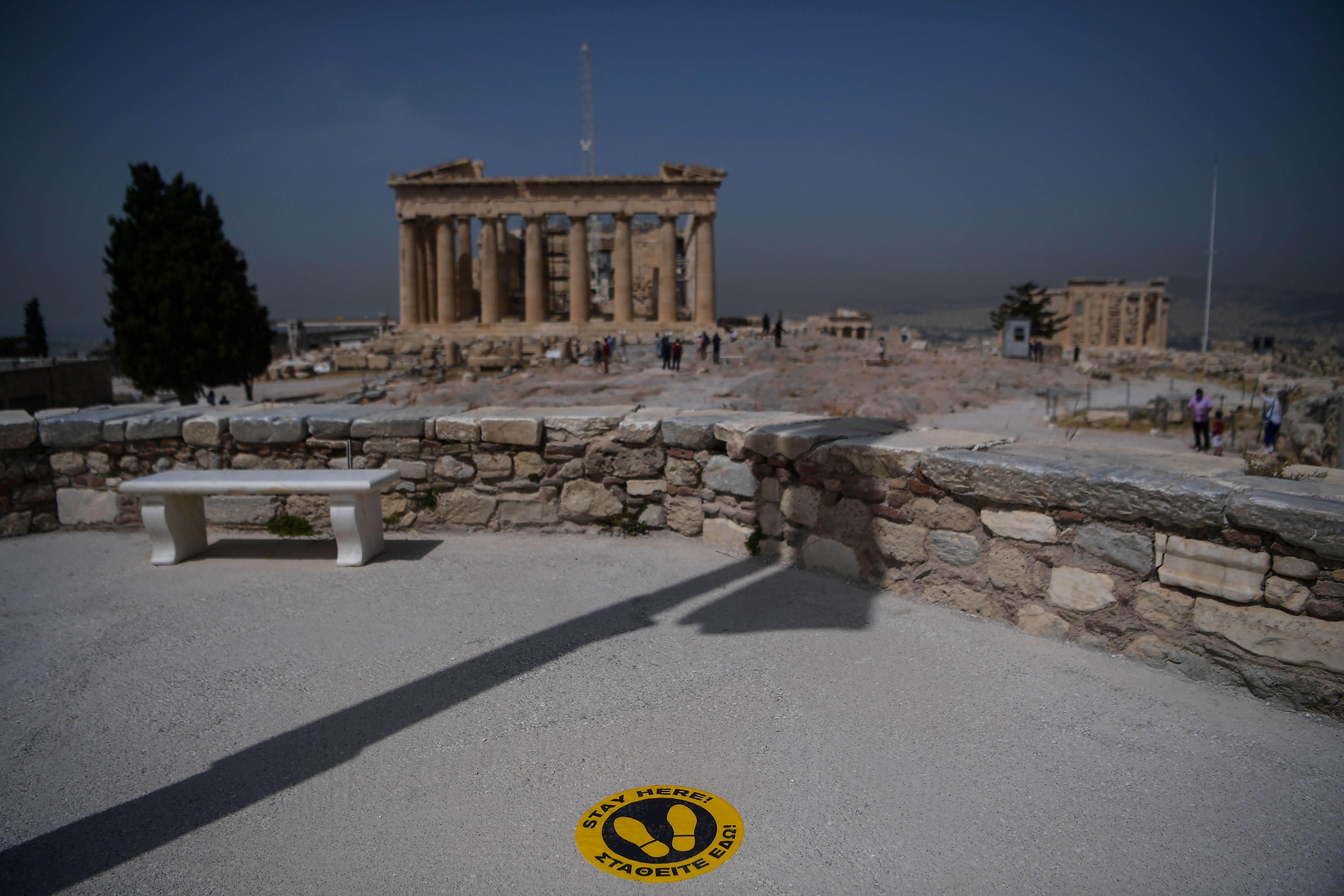 A picture taken on May 18, 2020 shows a sticker marking social distance on the ground in front of the Parthenon temple on the archeological site of the Acropolis in Athens amid the pandemic of the novel coronavirus. (Aris MESSINIS / Getty Images via AFP)