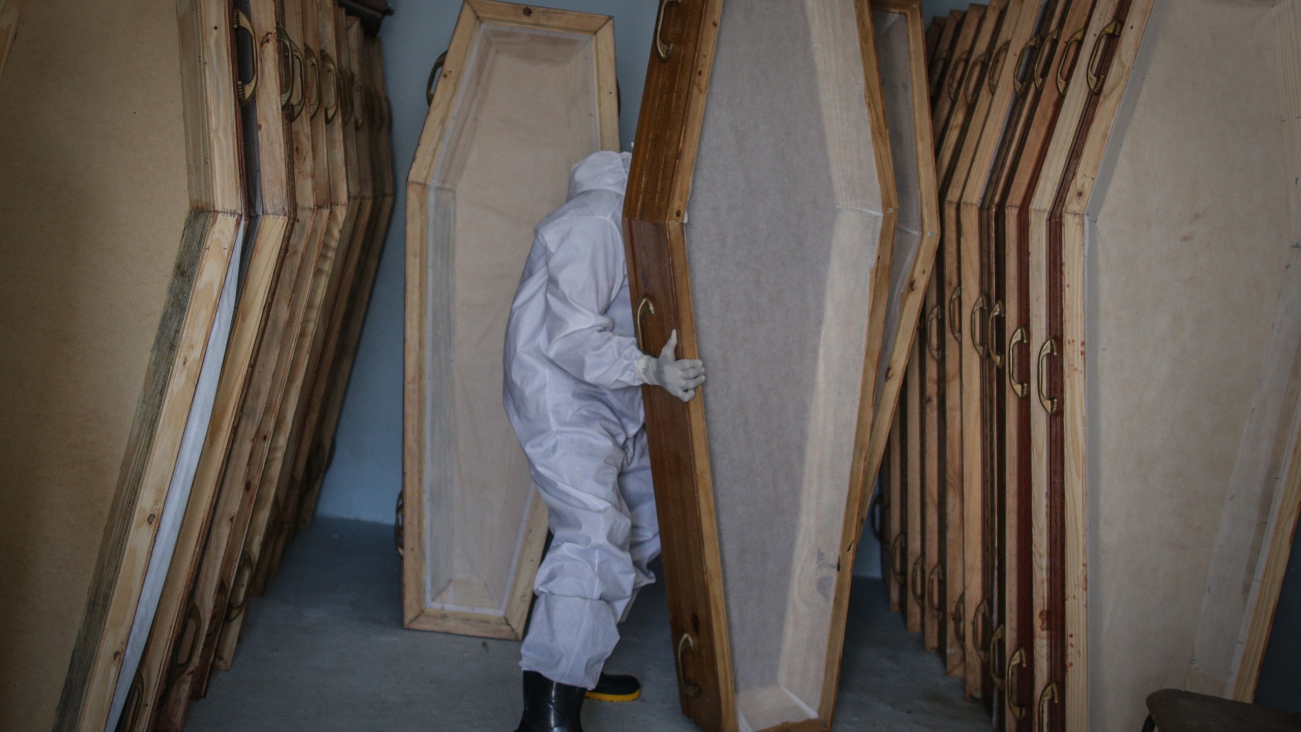 A member of SOS Funeral wearing a personal protective equipment holds an empty coffin at the team base deposit, on May 22 2020 in Manaus, Brazil. (Andre Coelho/Getty Images)