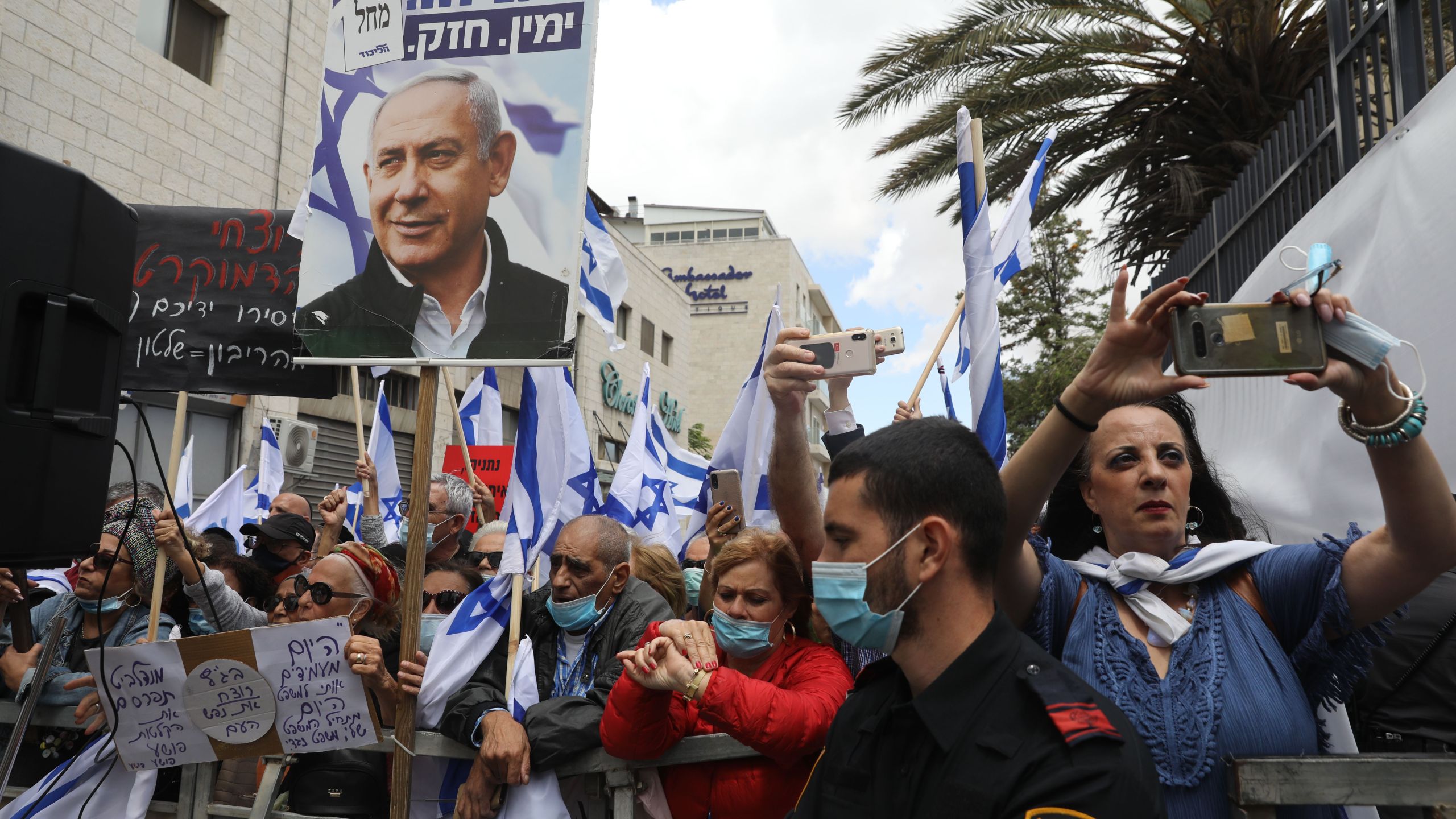 Israeli supporters hold flags and placards during a rally in support of Prime Minister Benjamin Netanyahu outside the district court of Jerusalem on May 24, 2020. (MENAHEM KAHANA/AFP via Getty Images)