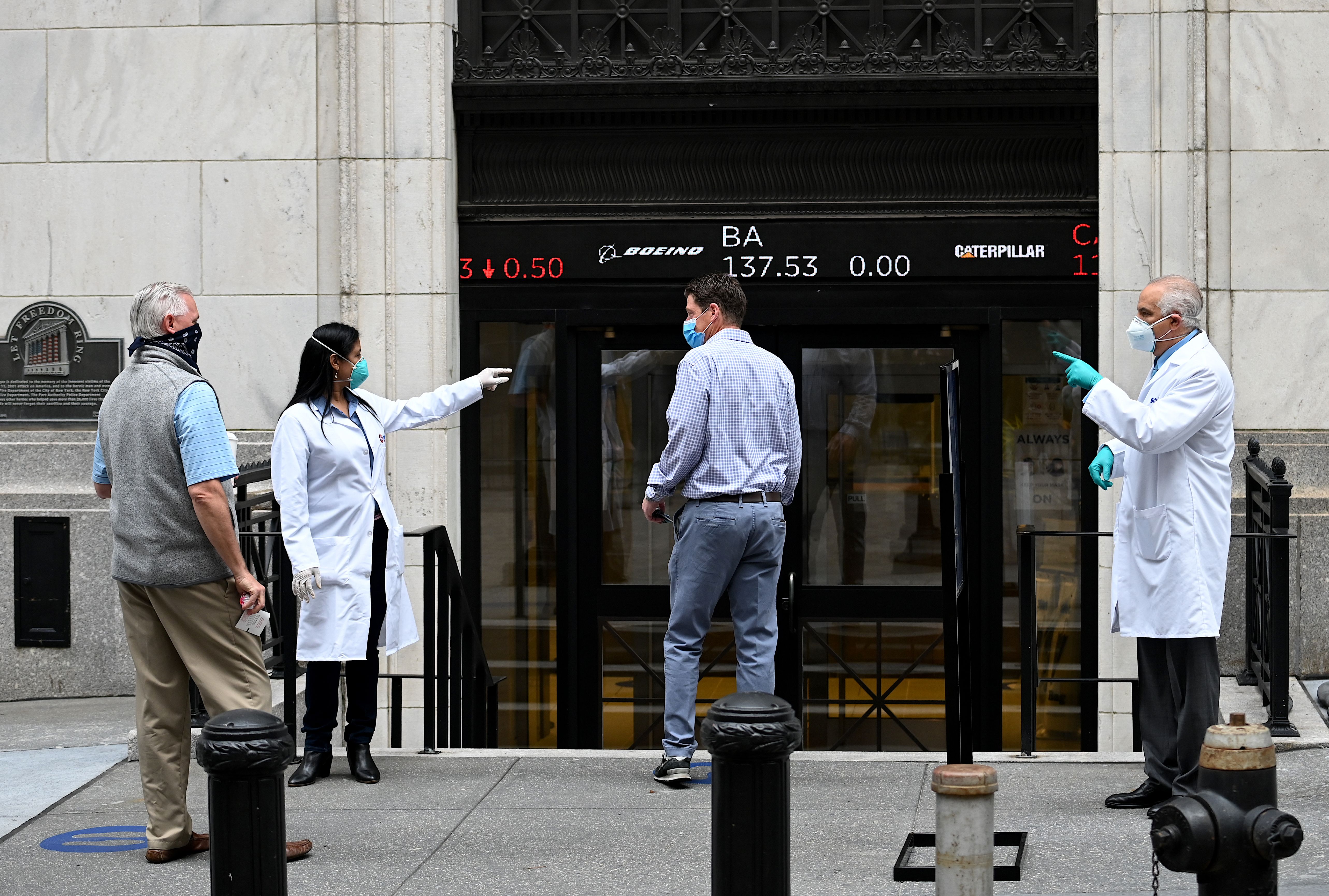 Medical workers check traders wearing masks as they arrive before the opening bell at the New York Stock Exchange on May 26, 2020 at Wall Street in New York City. (JOHANNES EISELE/AFP via Getty Images)