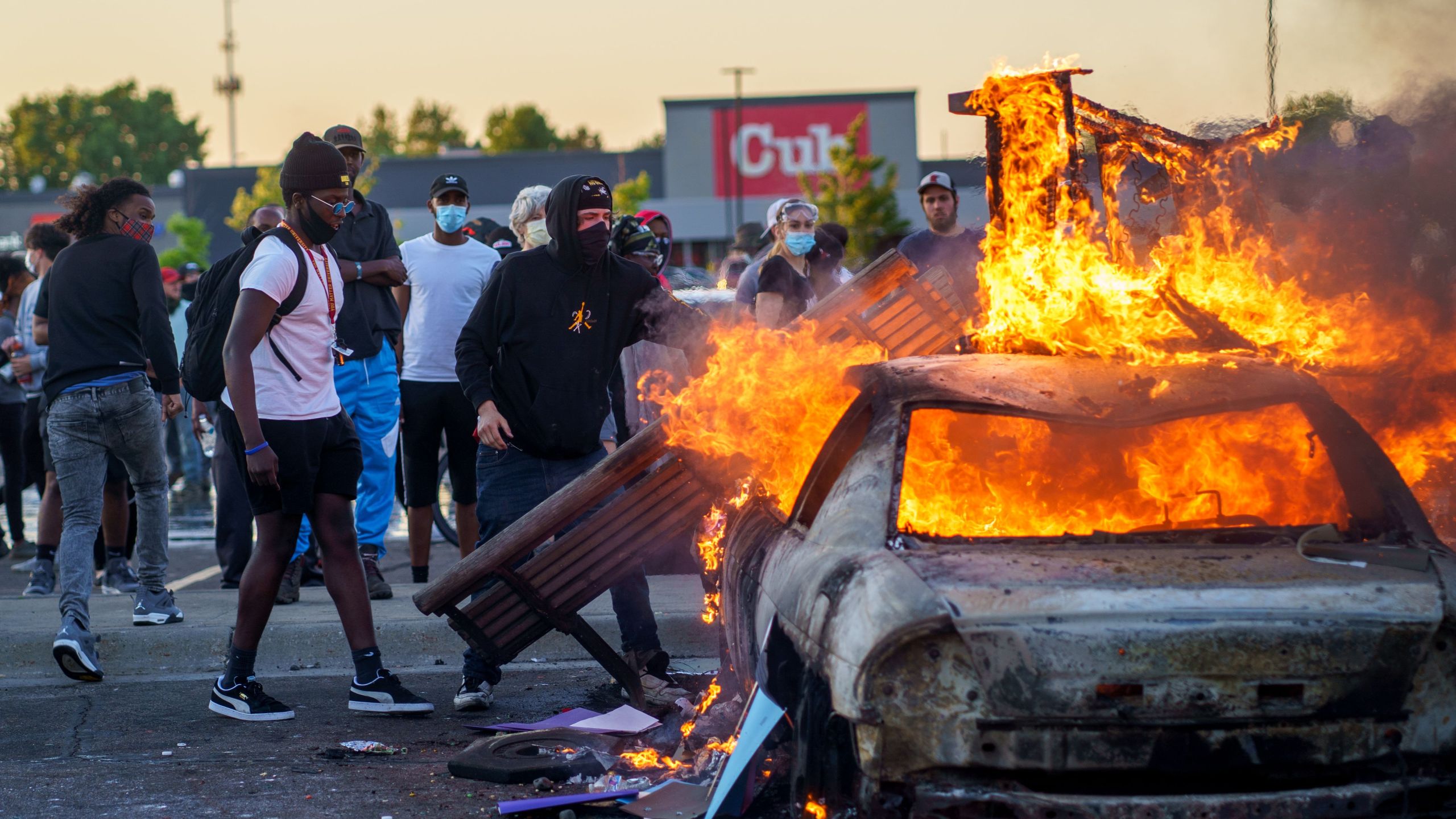 Protesters throw objects onto a burning car outside a Target store near the Third Police Precinct in Minneapolis, Minnesota, on May 28, 2020, during a demonstration over the death of George Floyd. (Kerem Yucel / AFP / Getty Images)