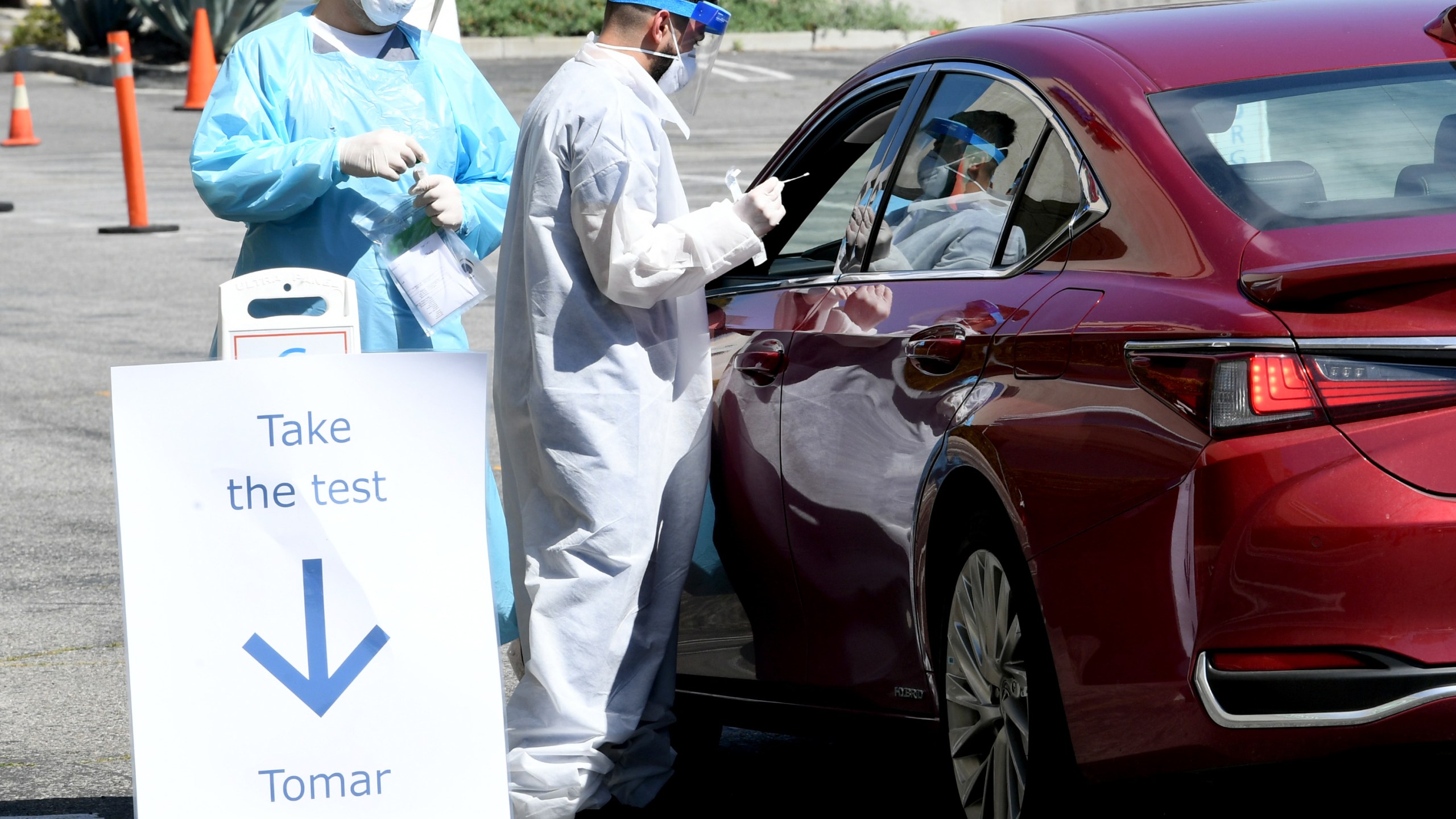 Workers wearing personal protective equipment (PPE) perform drive-up COVID-19 testing administered from a car at Mend Urgent Care testing site for the novel coronavirus at the Westfield Fashion Square on April 14, 2020 in the Sherman Oaks neighborhood of Los Angeles, California. (Kevin Winter/Getty Images)