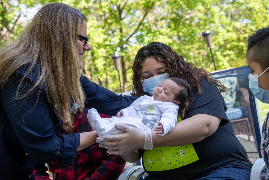 Elementary school teacher Luciana Lira hands Neysel, six weeks, to his mother Zully to hold for the first time on May 14, 2020 in Stamford, Connecticut. Zully and her family, now all testing Covid-negative, met Neysel and brought him home from Lira's house, where she has cared for him since his birth. Zully had tested positive for coronavirus in April 2020. (John Moore/Getty Images)