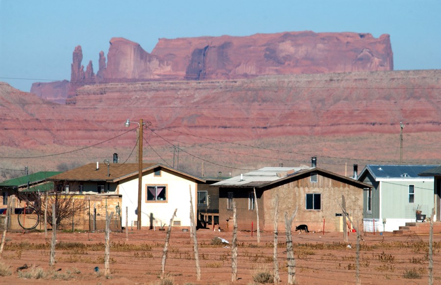 Houses are backed by sandstone cliffs on the Navajo Reservation in Arizona on Dec. 5, 2002. (David McNew/Getty Images)