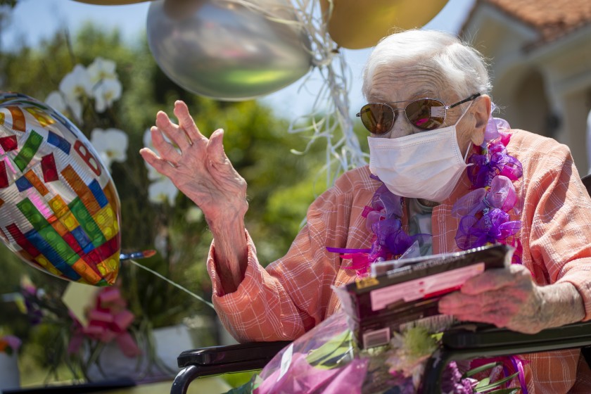 Mildred Stratton waves to a caravan of cars led by the Alhambra police and fire departments parading past her home, celebrating her 102nd birthday on May 20 in Alhambra.(Allen J. Schaben / Los Angeles Times)