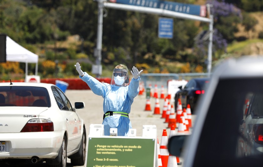 A person directs traffic at a drive-through coronavirus testing site at Dodger Stadium. (Christina House / Los Angeles Times)