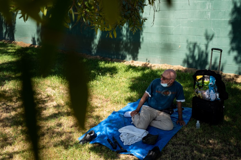 Terrance Whitten rests in the shade at Pan Pacific Park on May 1, 2020, in Los Angeles. The 67-year-old has been waiting in the queue for nine days to get into a hotel room. (Kent Nishimura / Los Angeles Times)